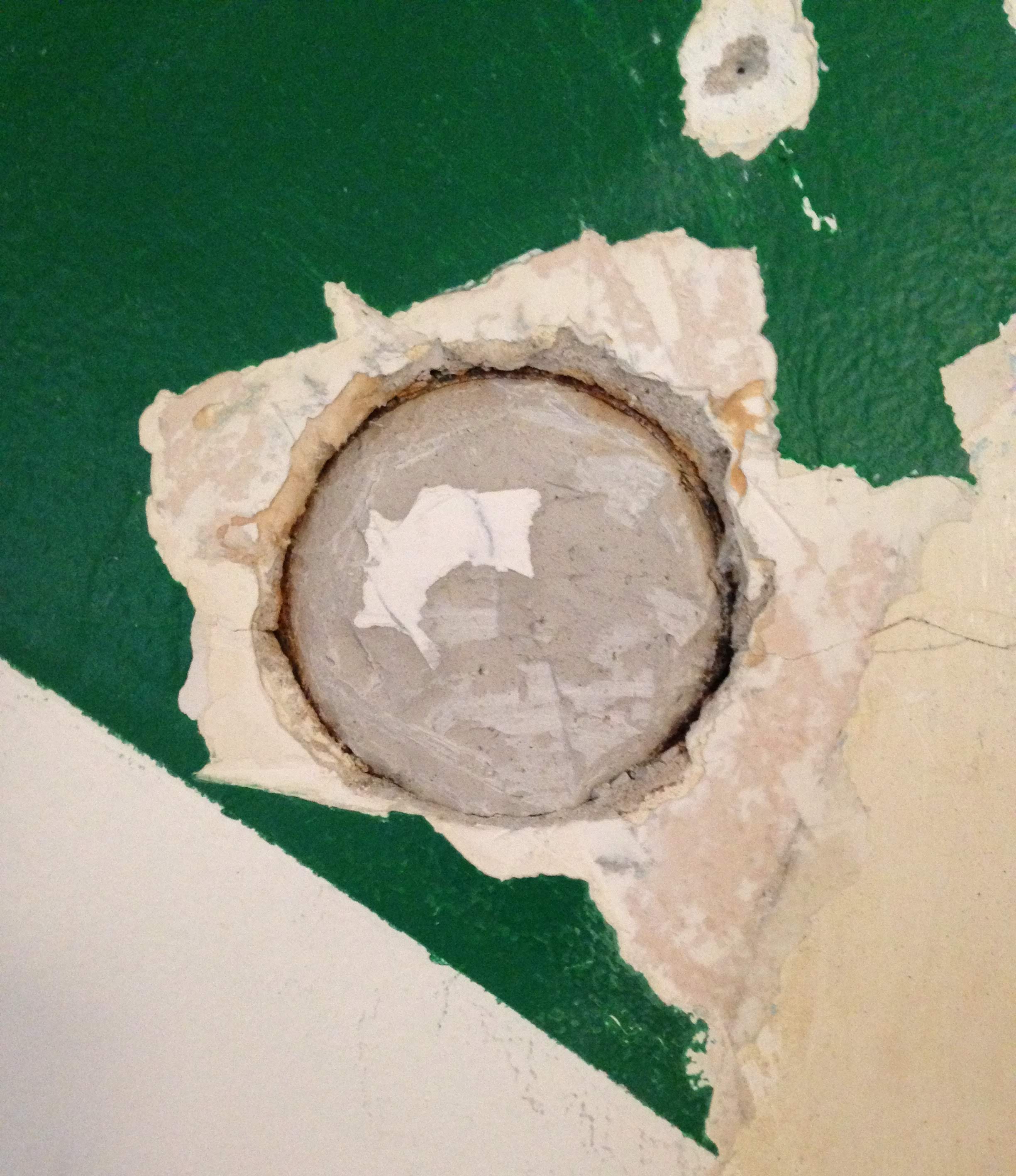 Scraping off the green paint revealed a round electrical box filled with plaster. 